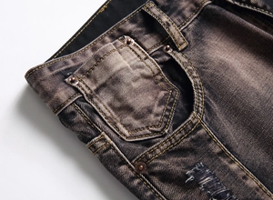 Close-up of men's distressed jeans featuring vintage rivets and yellow double stitching