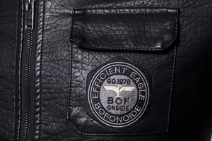 Close-up of motorcycle jacket pocket with eagle embroidery and metallic zipper detail