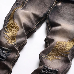 Men's vintage distressed jeans with gold wing embroidery and metallic studs detail