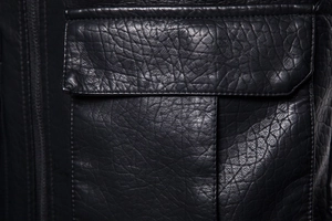 Macro shot of black biker jacket pocket with premium litchi texture and fine stitching