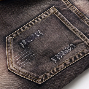 Men's distressed denim jeans featuring vintage washed finish and embroidered wing details