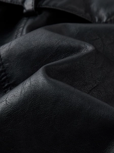 Detailed close-up of premium black PU leather texture with fine stitching on a trench coat