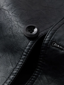Macro shot of black leather jacket detail with button, buttonhole, and lychee texture
