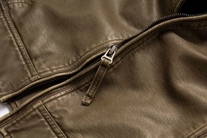 Detailed macro view of heavy-duty metal zipper and grain texture on faux leather jacket