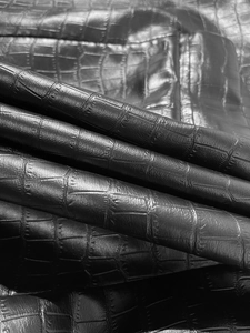 Detailed close-up of premium black crocodile pattern faux leather fabric with subtle gloss