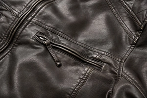 Macro view of brown faux leather jacket featuring chest zipper pocket and diamond stitching
