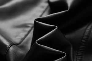 Close-up of premium black PU leather texture with fine grain and detailed stitching