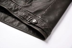 Detailed close-up of dark faux leather jacket hem with silver metal snap buttons and buckles