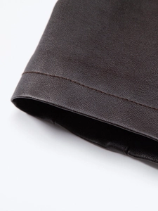 Macro shot of dark brown PU leather texture and precise stitching on biker jacket sleeve