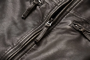 Macro shot of vintage dark brown faux leather texture and sturdy metal zipper detail