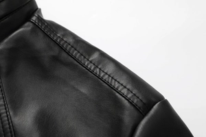 Macro view of double stitching detail on a black PU leather motorcycle jacket shoulder