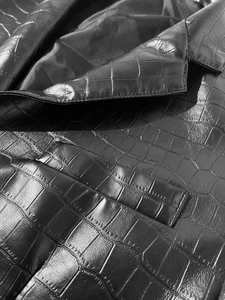 Macro detail of men's crocodile embossed leather jacket with precise shoulder stitching