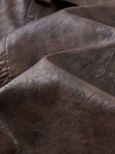Close-up of dark brown PU leather texture with detailed stitching on men's trench coat