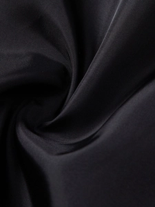 Close-up detail of smooth black PU leather texture with elegant spiral fabric folds
