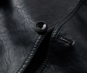Detailed close-up of textured black PU leather fabric and round button on trench coat