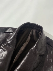 Detail view of deep brown faux crocodile skin texture and notched lapel on men's jacket
