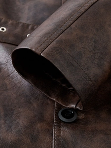 Detailed macro view of vintage brown PU leather jacket with stitching and button details