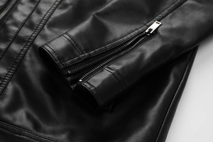 Close-up of black PU leather motorcycle jacket featuring metal zipper cuffs and texture