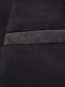Detailed close-up of brown lychee grain faux leather panel stitched on a black men jacket