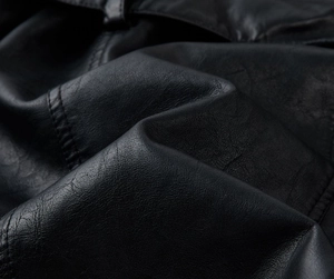 Close-up of premium black PU leather texture with detailed stitching on trench coat