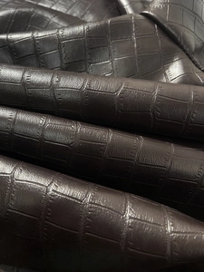 Macro view of dark brown faux crocodile embossed leather texture with matte finish