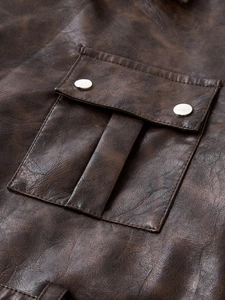 Detail of vintage brown PU leather trench coat showing square pocket and metal buttons