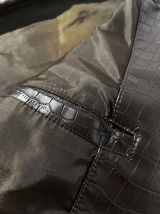 Detail of faux crocodile embossed leather with reinforced stitching and brown lining