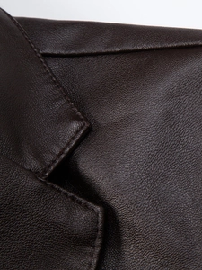 Close-up of premium dark brown PU leather jacket showing fine stitching and lychee grain texture