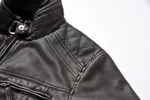 Detail of vintage black leather jacket showing stand collar with metal snap and quilted shoulder