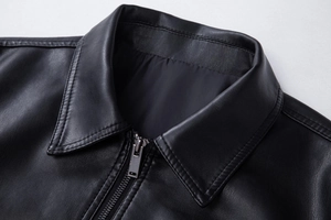 Detailed close-up of a classic black PU leather jacket lapel with silver metal zipper