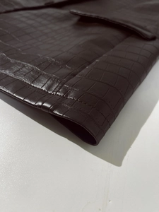 Macro shot of dark brown faux leather jacket featuring realistic crocodile embossed texture