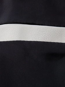 Macro detail of the black fabric and white lychee pattern faux leather texture on the jacket
