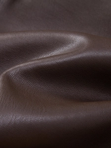 Dettaglio macro della trama in pelle PU marrone scuro con grana naturale per giacca uomo