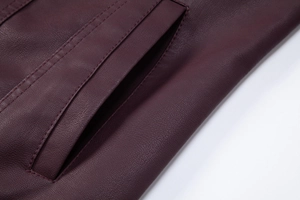 Macro detail of burgundy PU leather jacket featuring reinforced double-stitched pocket seams