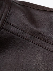 Macro detail of dark brown PU leather jacket with premium litchi texture and fine stitching