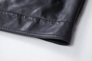 Close-up of the double-stitched hem and fine grain texture of the black PU leather jacket