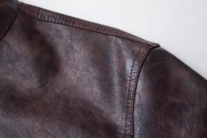 Close-up of double-stitched shoulder seams on a dark brown vintage PU leather jacket