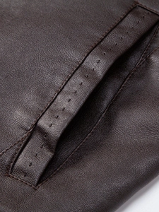 Macro detail of dark brown PU leather texture and precision stitching on the jacket