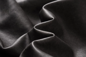 Macro detail of high-quality black PU leather texture with subtle grain and soft creases