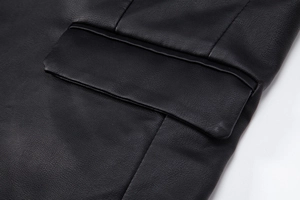 Détail d'une veste en similicuir noir montrant le grain et les coutures de la poche
