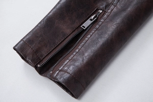 Close-up of deep brown vintage leather jacket sleeve with metallic zipper and cracked texture