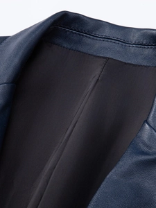 Close-up detail of dark blue PU leather jacket showing fine lychee texture and stitching