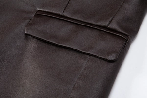 Gros plan sur le rabat de la poche et les coutures de la veste en cuir marron foncé texturé