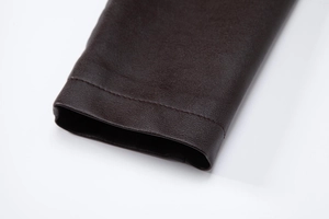 Détails de la texture du cuir PU marron foncé et des coutures sur le revers de la manche
