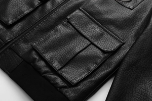 Detail of black faux leather flight jacket showing patch pocket and ribbed hem texture