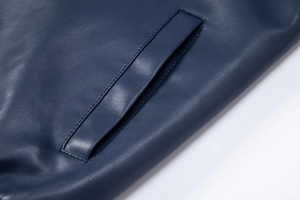 Macro shot of dark blue PU leather jacket with premium litchi texture and welt pocket detail