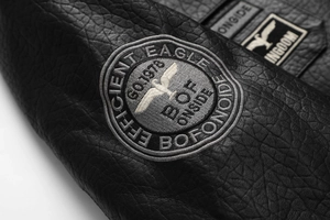 Close-up of eagle embroidery on black pebbled leather biker jacket showing fine texture