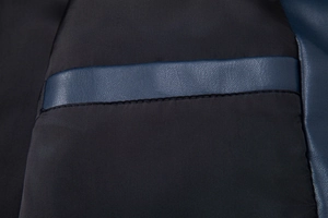 Detailed macro view of stitched faux leather texture and fabric seams on a jacket