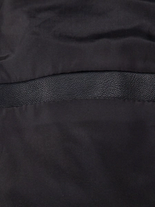 Detailed macro shot of premium black lychee-grain PU leather and fabric texture on jacket