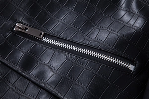 Detailed macro view of black faux crocodile leather jacket with silver metal zipper